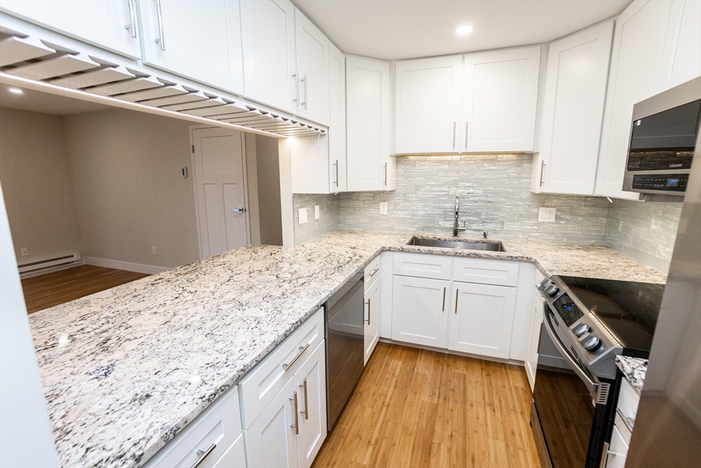 31 Hamlin Lane, Unit A33 Needham, MA 02492 - Photo 4 of 15 a kitchen with a sink stove and cabinets