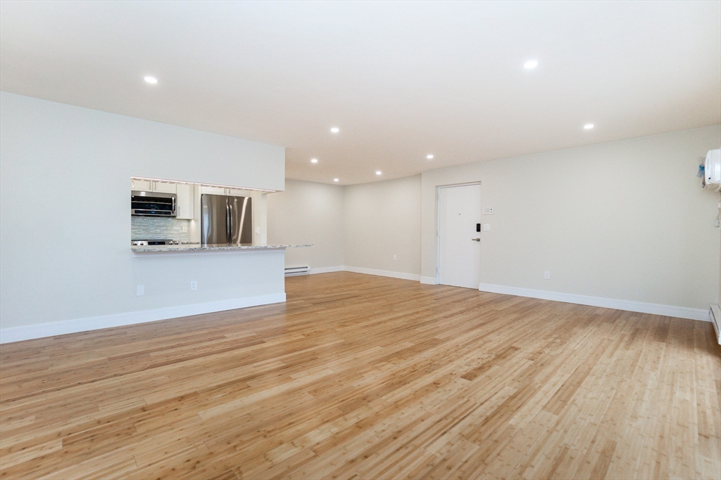 31 Hamlin Lane, Unit A33 Needham, MA 02492 - Photo 5 of 15 an empty room with wooden floor and a fireplace