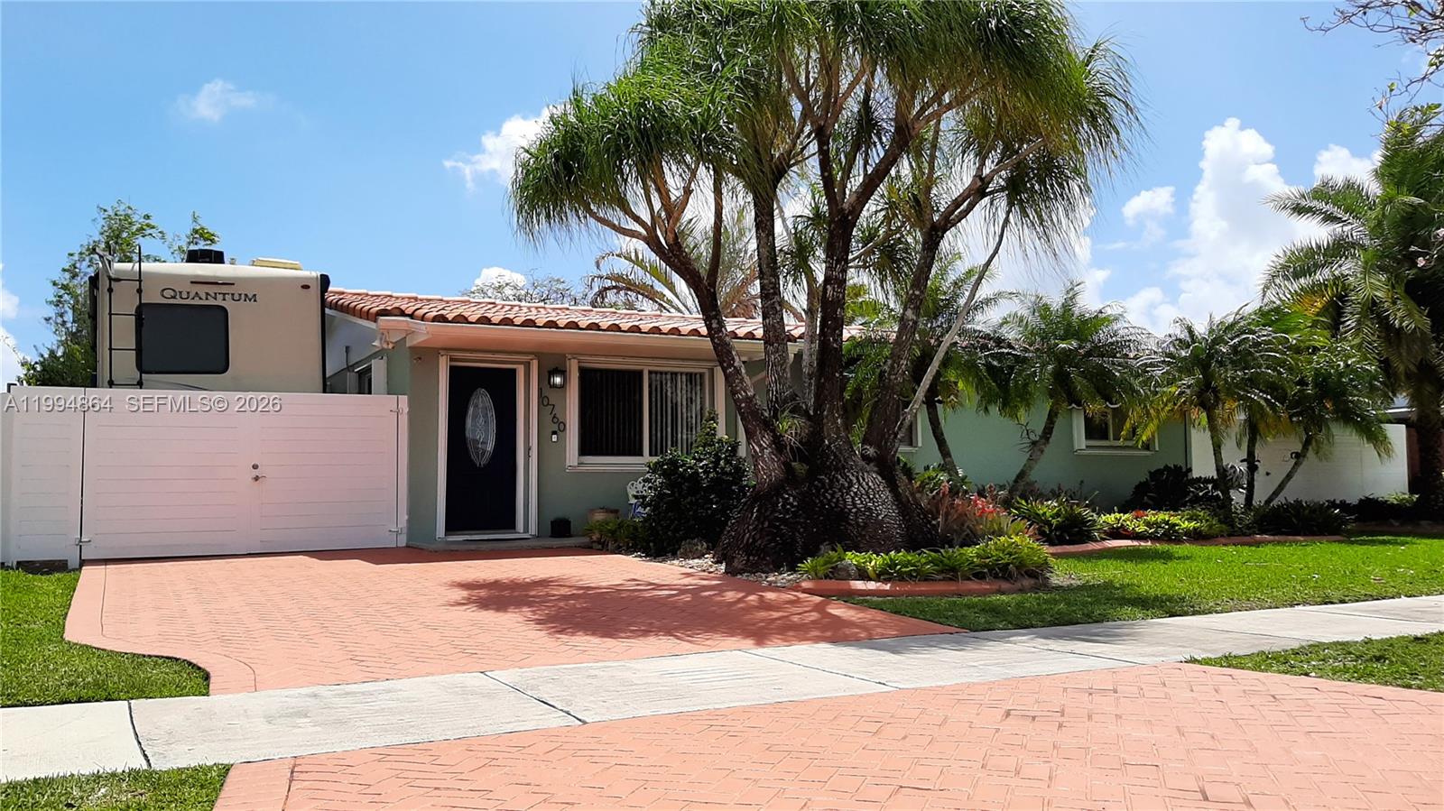 a front view of a house with a garden and palm trees
