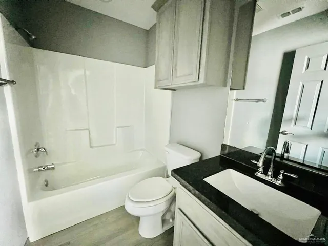 a bathroom with a granite countertop sink a toilet and bathtub