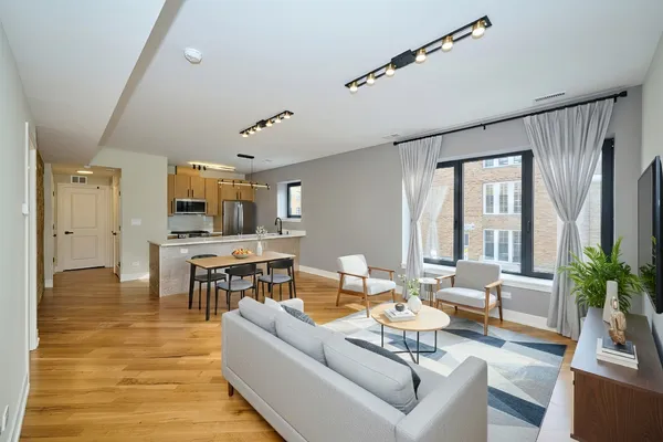 a living room with furniture kitchen view and a large window