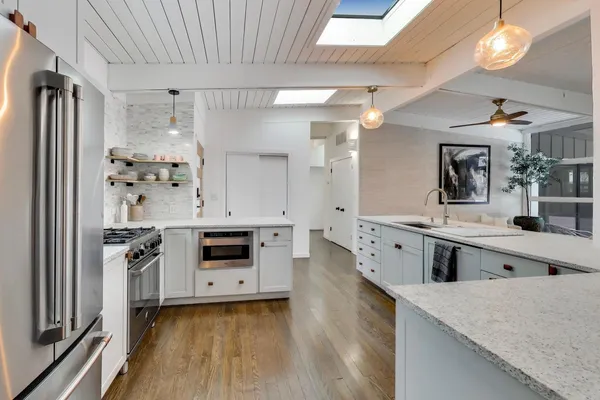 a large white kitchen with a white center island a stove a dining table and chairs