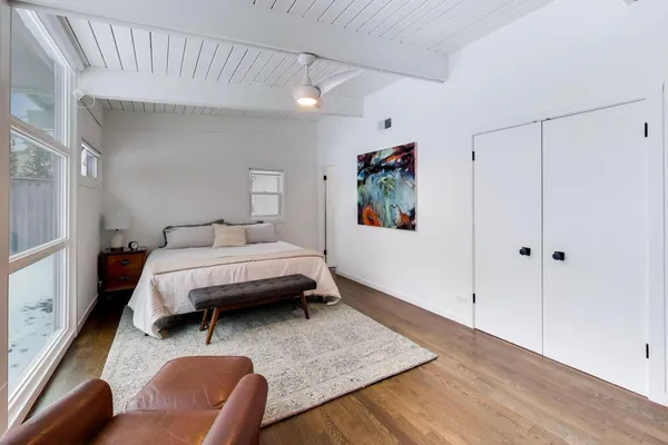 a bedroom with a large bed couch and two windows