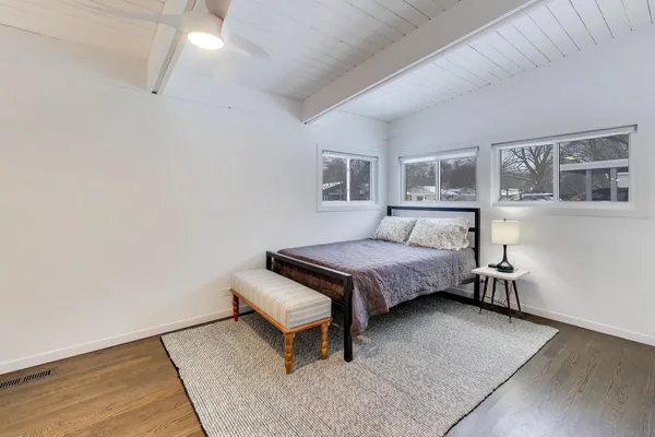 a bedroom with a bed a table and wooden floor