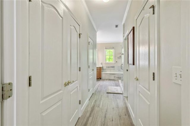 a spacious bedroom with a large bed a chandelier with dresser and mirror