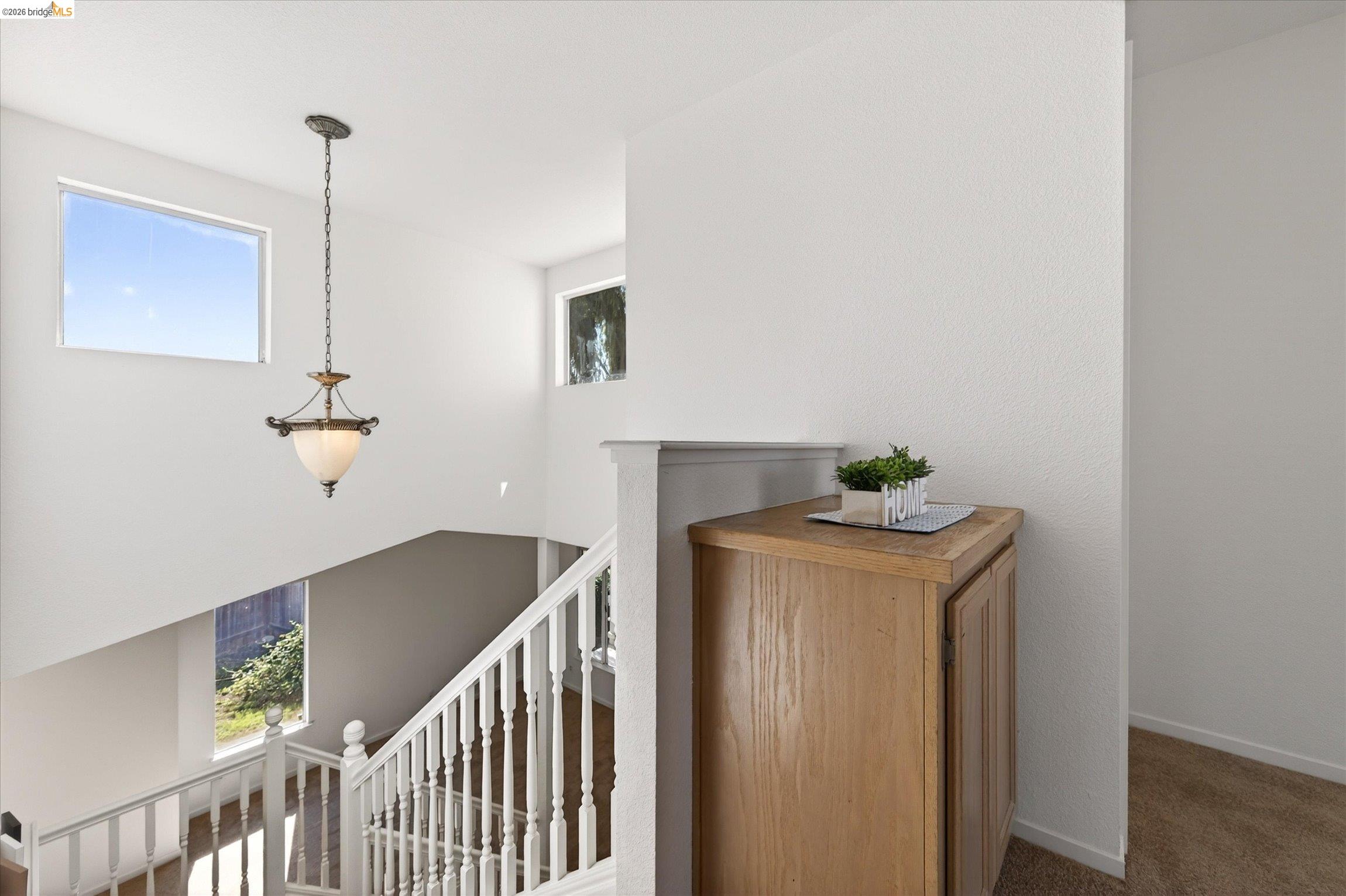 1120 Deerpark Road Oakley, CA 94561 - Photo 18 of 30 Stairwell featuring a decorative pendant light fixture, white balusters, and multiple windows providing natural illumination