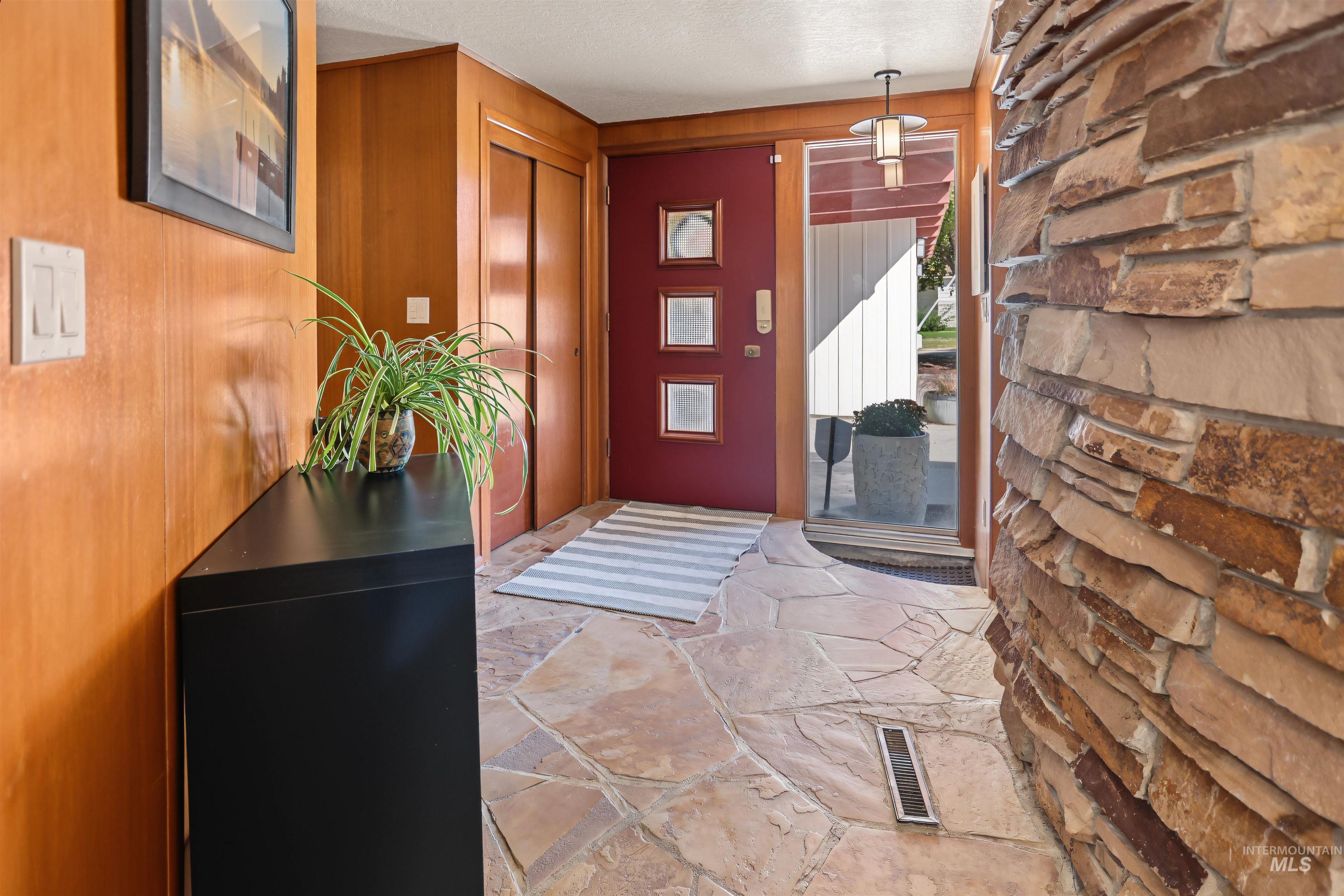 508 East Elm Avenue Parma, ID 83660 - Photo 4 of 50 Stacked stone wall with natural variations, flagstone flooring, wood-paneled walls, and a recessed ceiling light fixture