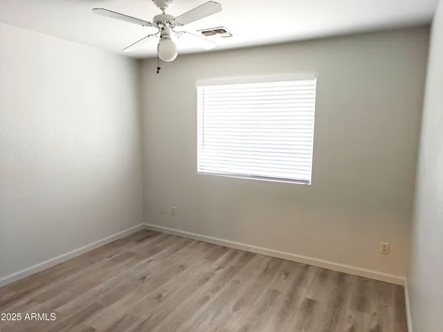 an empty room with a window and a fan