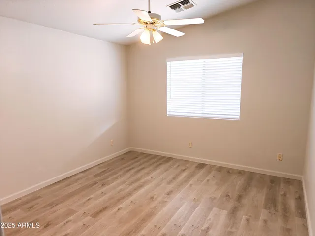 an empty room with a window and a fan