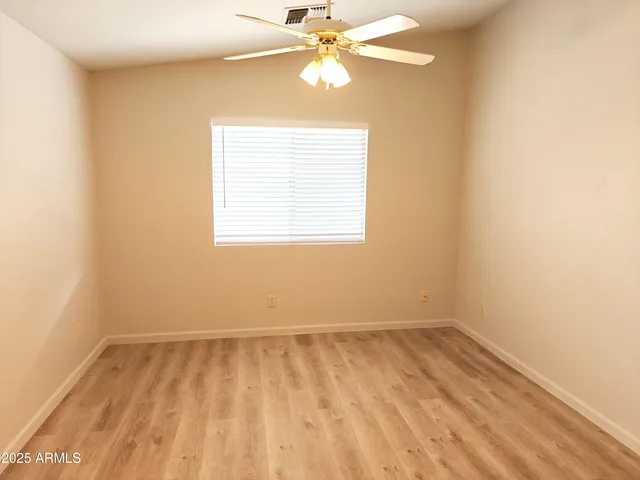 an empty room with a window and a ceiling fan
