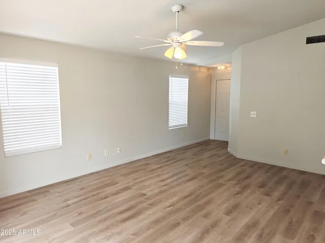 an empty room with wooden floor and windows