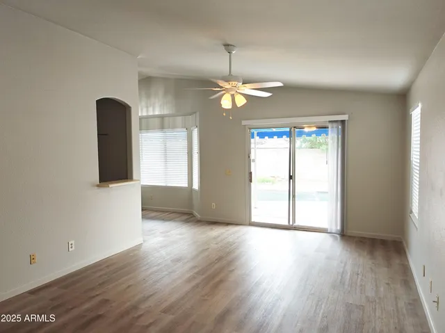 a view of an empty room with a window and wooden floor