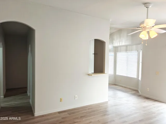 a view of an empty room with window and wooden floor