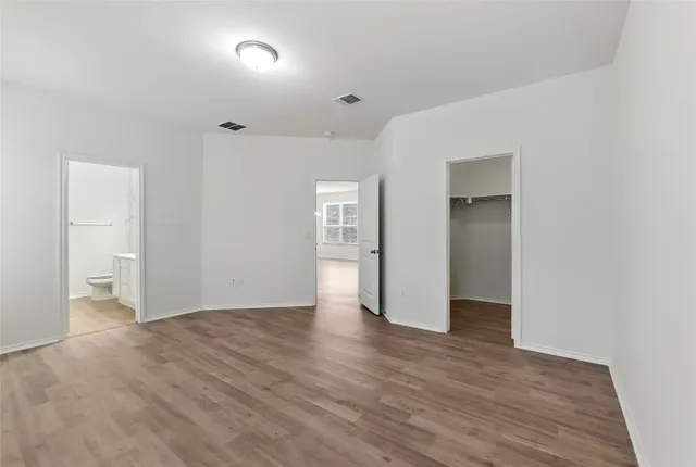 a view of an empty room with wooden floor and closet