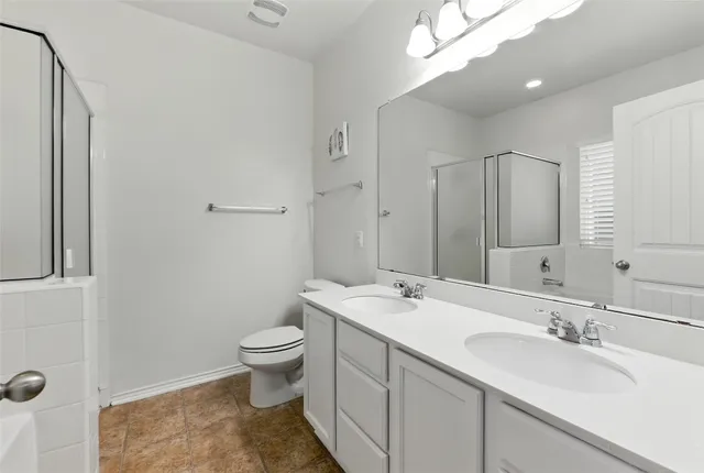 a bathroom with a sink a toilet a mirror and shower