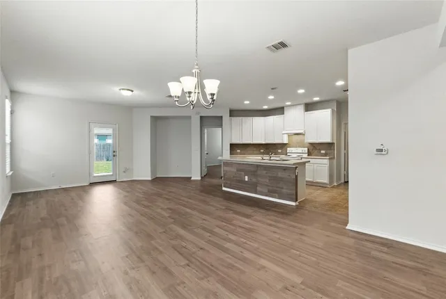 a large kitchen with stainless steel appliances granite countertop a large counter top and wooden floors