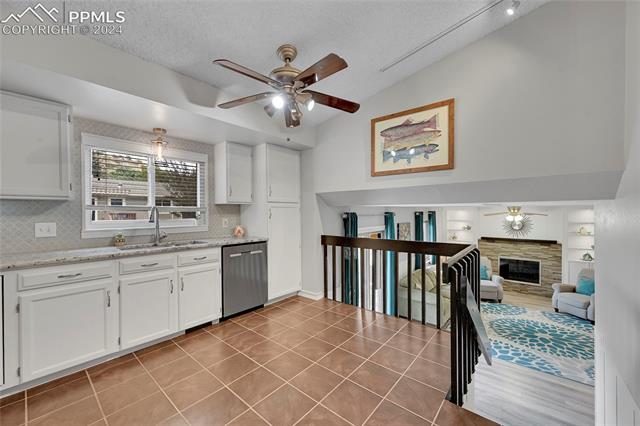5255 Pinon Valley Road Colorado Springs, CO 80919 - Photo 11 of 47 Kitchen featuring tasteful backsplash, stainless steel dishwasher, sink, a textured ceiling, and lofted ceiling