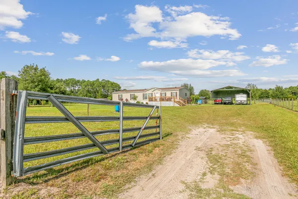 a view of a house with a big yard and large trees