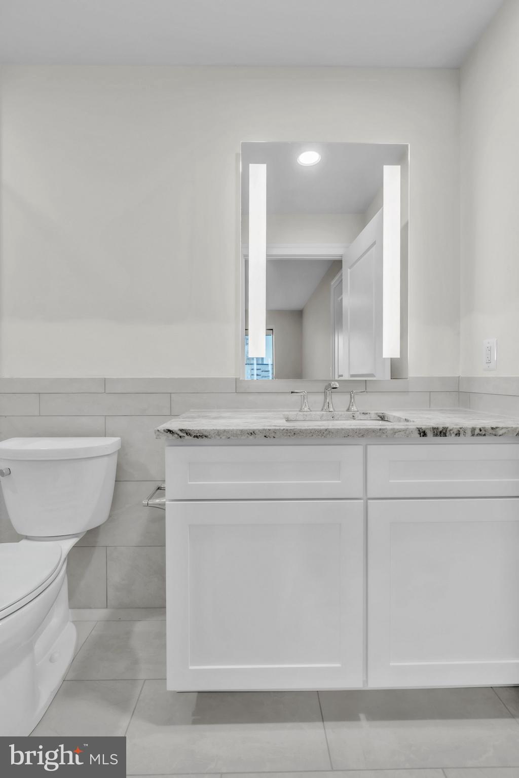 1801 Market Street, Unit 1817 Philadelphia, PA 19103 - Photo 12 of 77 a bathroom with a granite countertop toilet sink and mirror