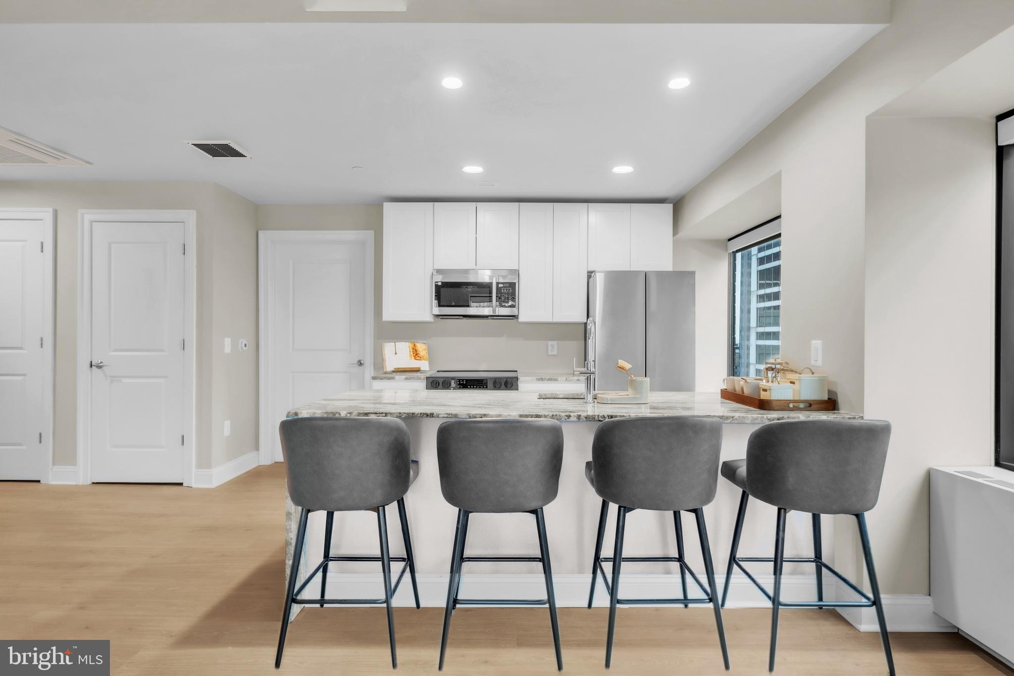 1801 Market Street, Unit 1817 Philadelphia, PA 19103 - Photo 6 of 77 a kitchen with stainless steel appliances granite countertop a stove a sink a refrigerator white cabinets and chairs