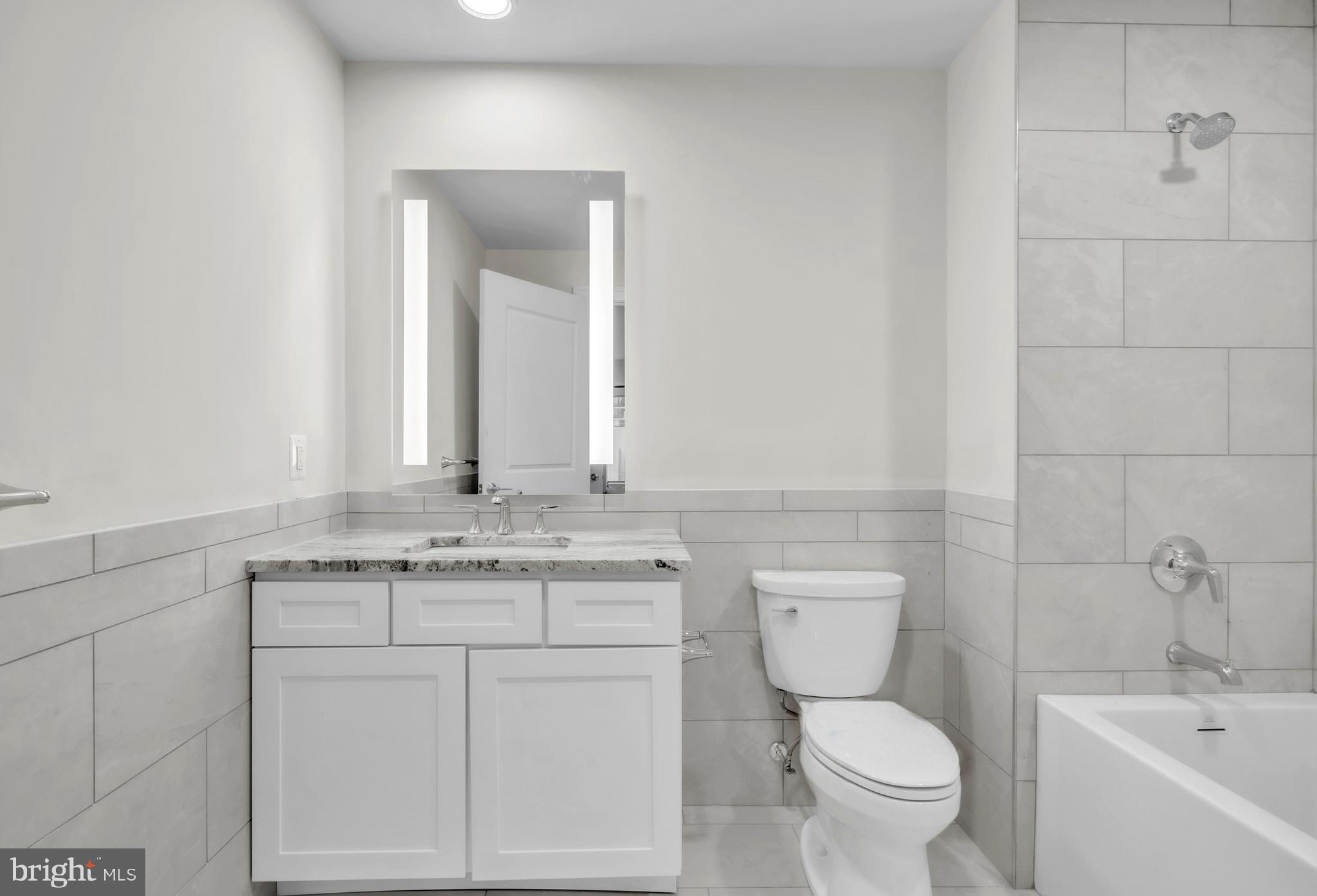 1801 Market Street, Unit 1817 Philadelphia, PA 19103 - Photo 10 of 77 a bathroom with a granite countertop toilet sink and mirror