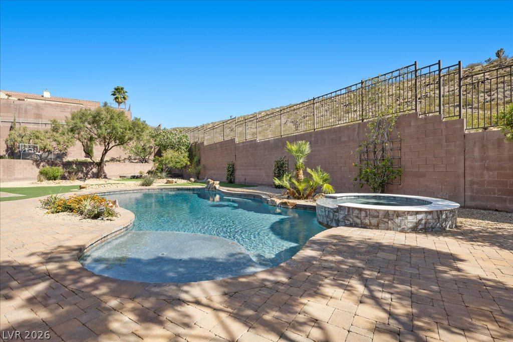 2125 De Rouge Avenue Henderson, NV 89044 - Photo 76 of 96 An inviting backyard oasis awaits with a custom pool and spa, framed by mature desert landscaping.