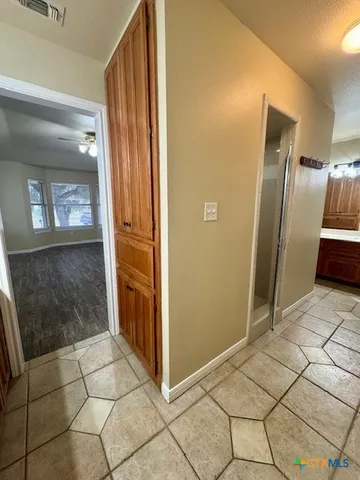 a view of a refrigerator in kitchen and an empty room in wooden floor