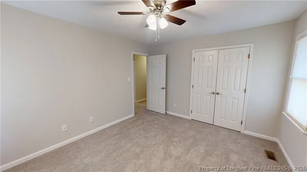 a view of an empty room and chandelier fan