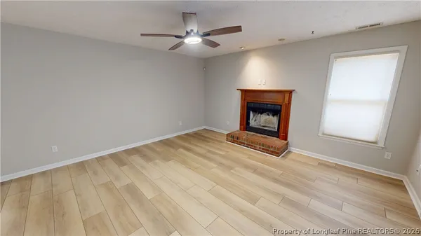 a view of an empty room with a fireplace and a window