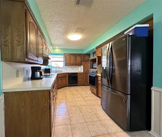 a kitchen with stainless steel appliances granite countertop a refrigerator a stove and a sink