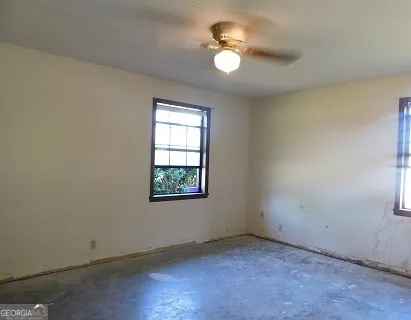 an empty room with windows and fan