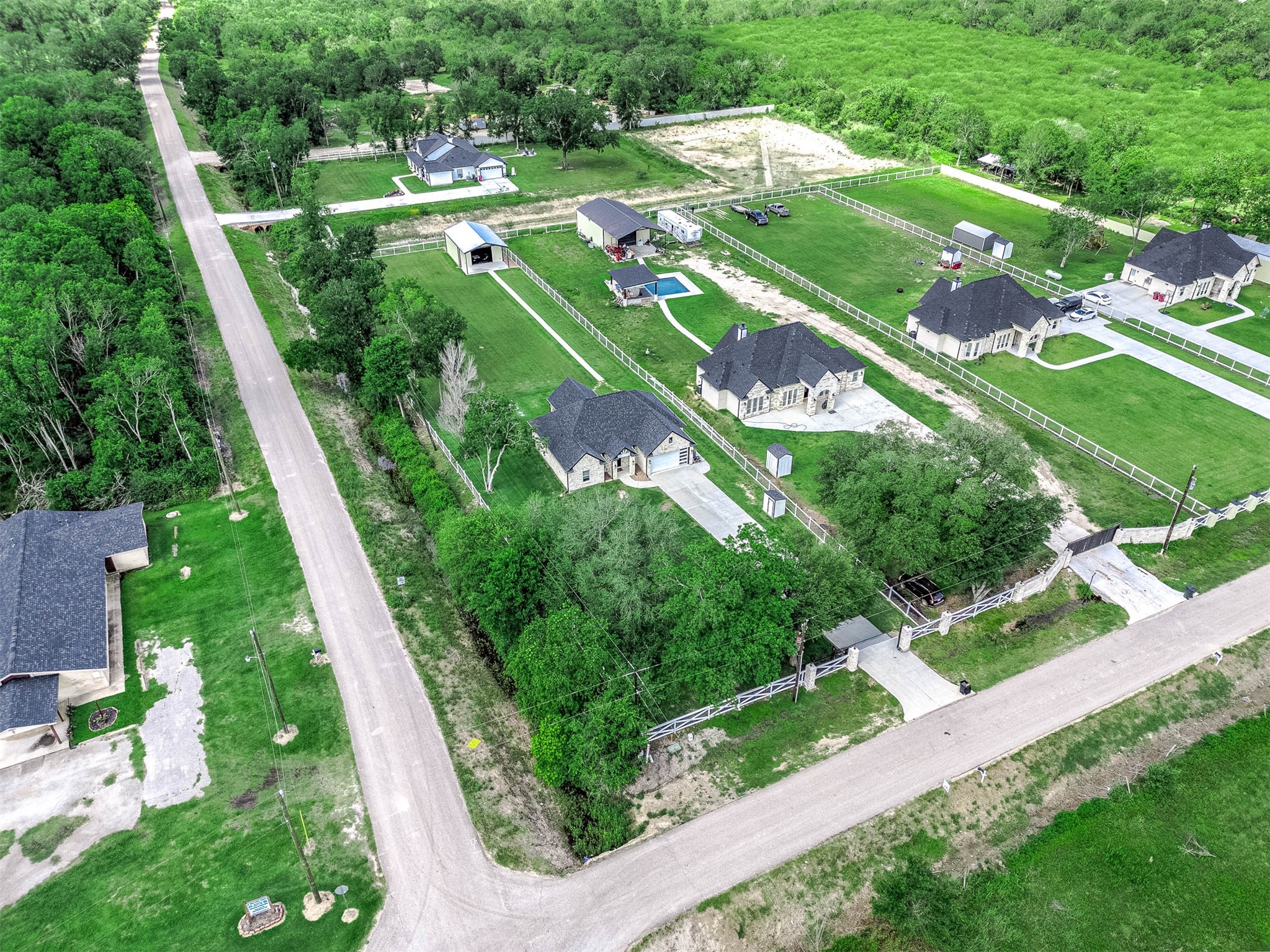 8032 Short Road Needville, TX 77461 - Photo 41 of 50 This aerial view highlights the property’s spacious setting, showcasing the home’s placement on the acreage along with the surrounding greenery and neighboring estate-style properties. The peaceful location and open surroundings offer a quiet retreat with plenty of space to enjoy.
