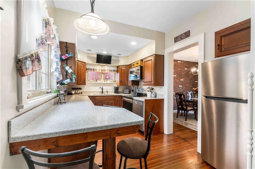 201 4th Street Beaver, PA 15009 - Photo 14 of 42 a kitchen with stainless steel appliances granite countertop a refrigerator a stove a sink dishwasher a dining table and chairs with wooden floor