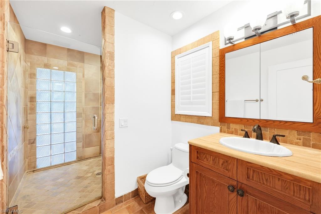 4870 Whispering Pine Way Naples, FL 34103 - Photo 18 of 43 a bathroom with a granite countertop sink toilet and shower