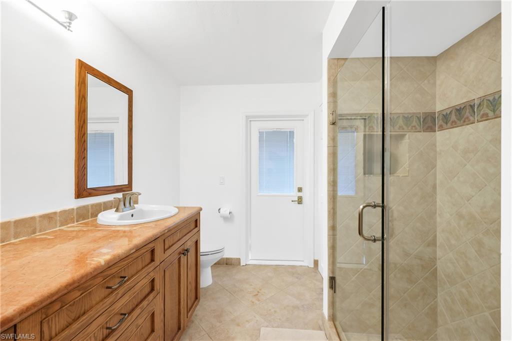 4870 Whispering Pine Way Naples, FL 34103 - Photo 25 of 43 a bathroom with a granite countertop sink a mirror and a shower