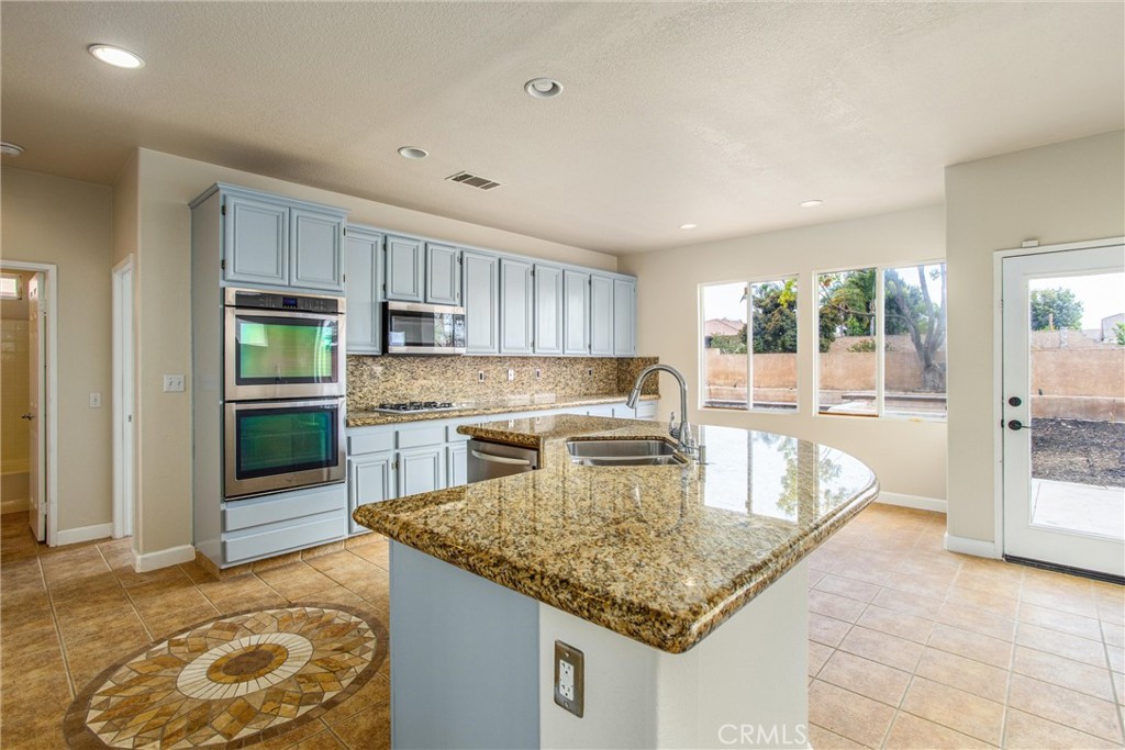 19429 Norwich Drive Riverside, CA 92508 - Photo 15 of 45 a kitchen with kitchen island granite countertop wooden cabinets a stove and a sink