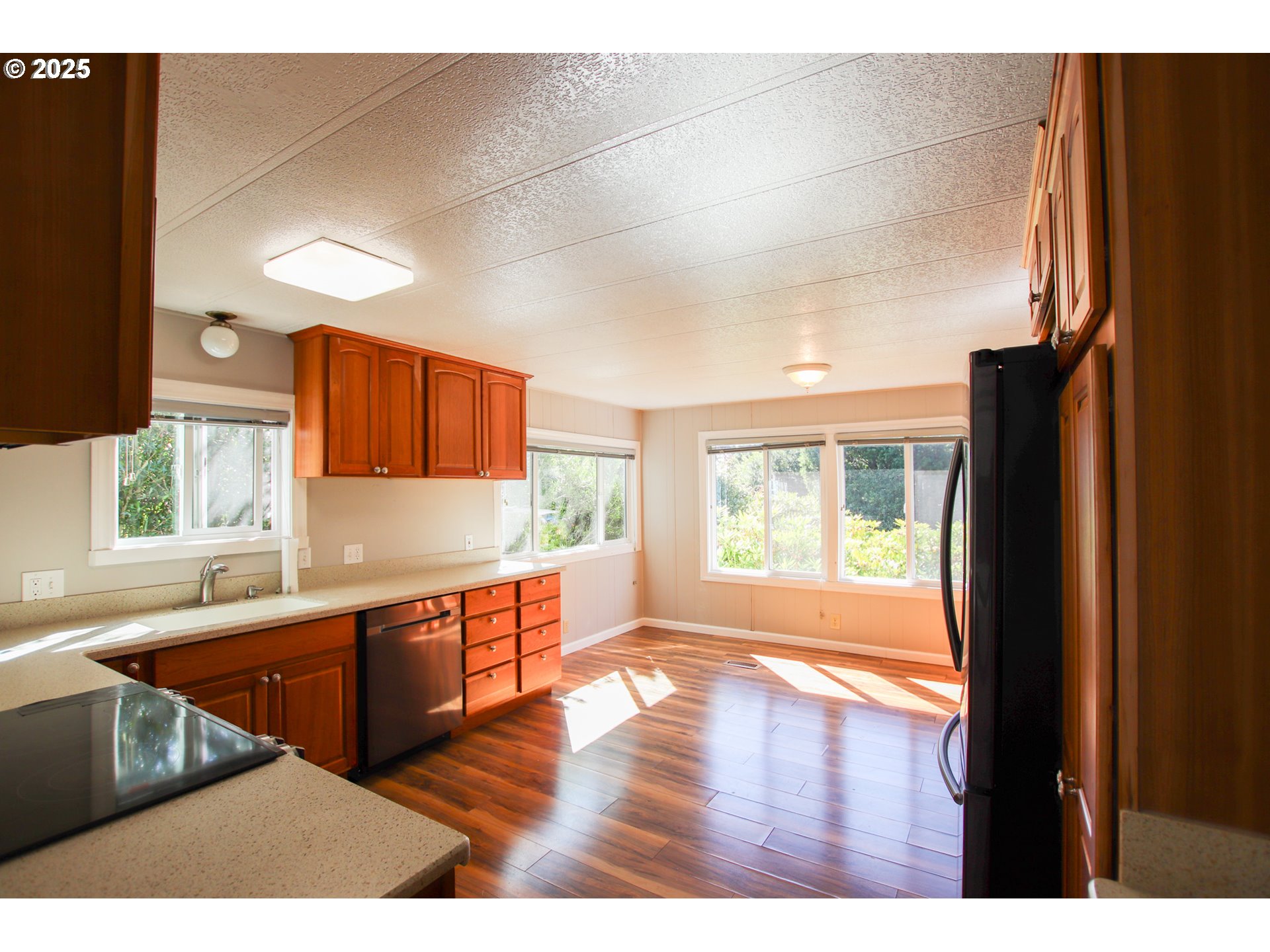 1600 Rhododendron Drive, Unit 279 Florence, OR 97439 - Photo 10 of 30 a kitchen with stainless steel appliances granite countertop a refrigerator a sink dishwasher a stove and white countertops with wooden floor