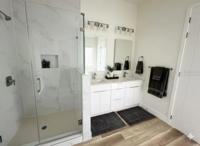 a bathroom with a double vanity sink mirror and shower