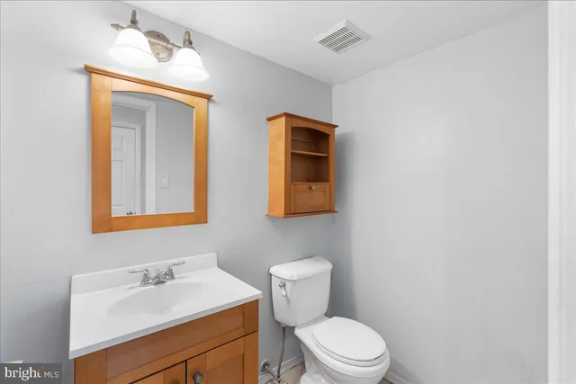 a bathroom with a toilet sink vanity and mirror