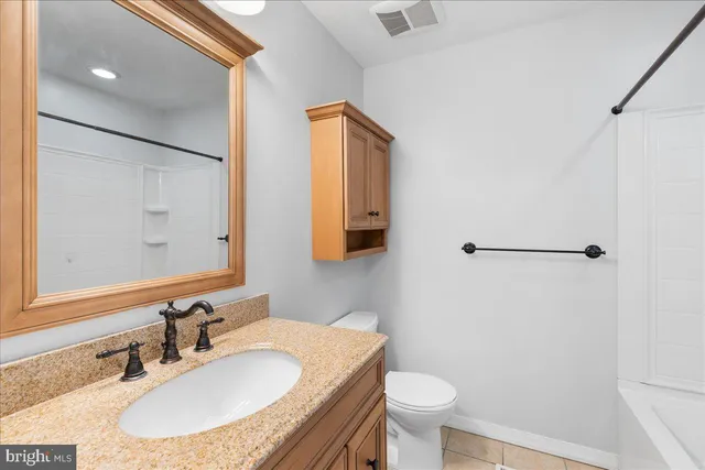 a bathroom with a granite countertop sink toilet and a mirror