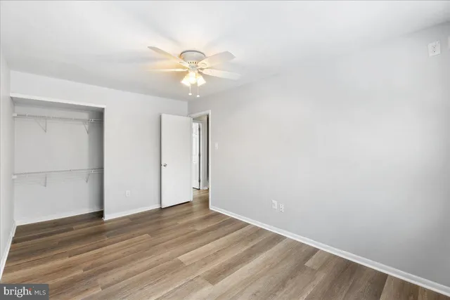an empty room with wooden floor and fan