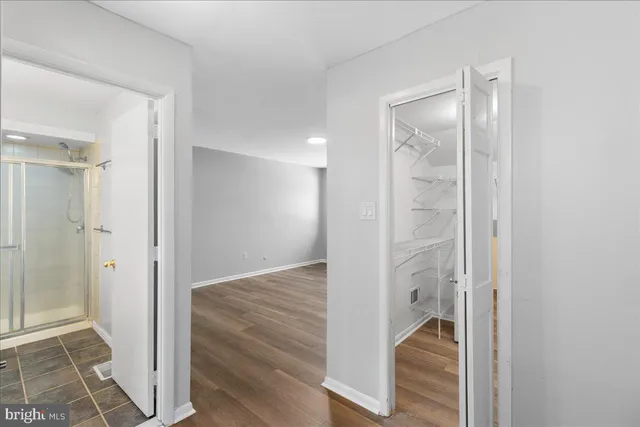 a view of a hallway with wooden floor and a bathroom