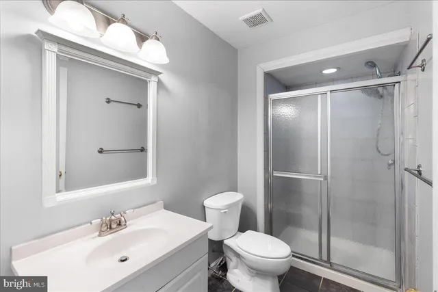 a bathroom with a shower sink vanity mirror and toilet