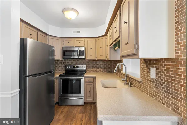 a kitchen with a refrigerator sink and wooden floor