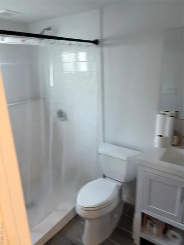 a white toilet sitting next to a shower