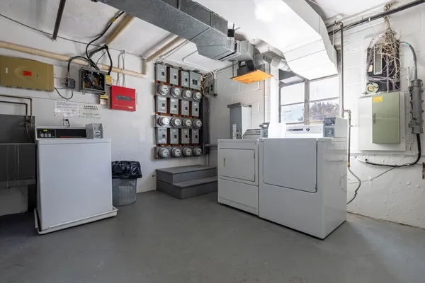 a kitchen that has a lot of white cabinets and stainless steel appliances