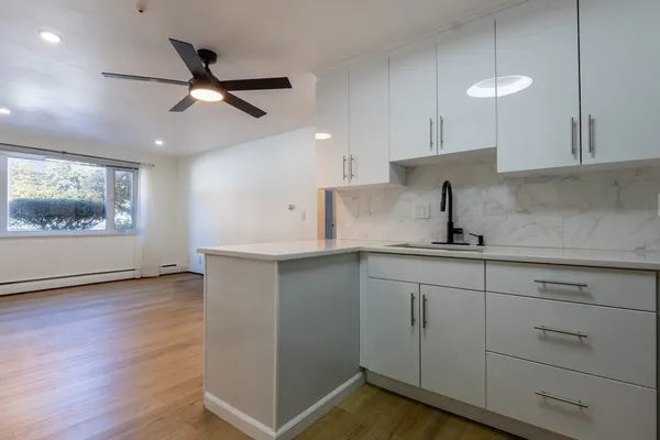 a kitchen with cabinets wooden floor and a window