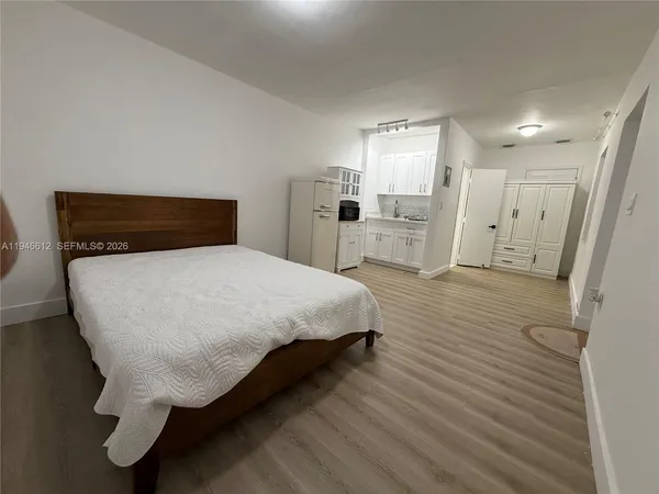 a bed sitting in a spacious bedroom next to a bathroom sink