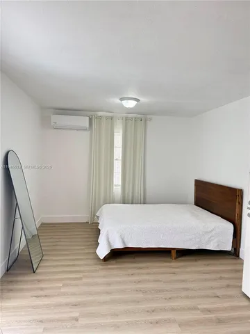 a room with a bed a lamp and wooden floor