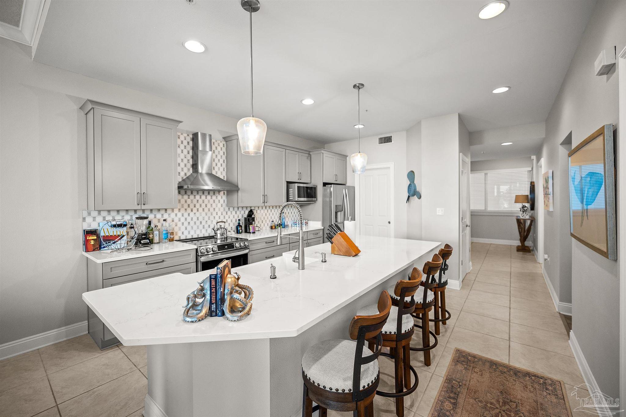 28250 Canal Road, Unit 205 Orange Beach, AL 36561 - Photo 12 of 60 a kitchen with stainless steel appliances kitchen island granite countertop a table chairs in it and wooden floors